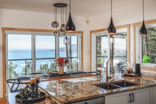 a kitchen with windows and a counter with a sink at Villa Experience Nature Le Nid in Saint-Irénée