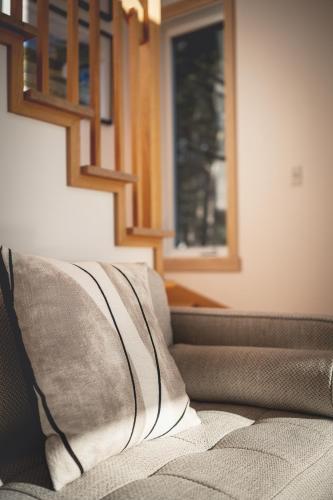 a couch with two pillows on it in a room at Villa Experience Nature Le Nid in Saint-Irénée