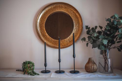 a mirror on a wall with two candlesticks and a plant at Villa Experience Nature Le Nid in Saint-Irénée