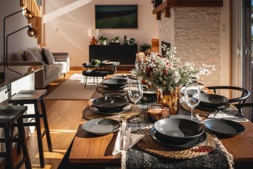 a dining room table with black plates and wine glasses at Villa Experience Nature Le Nid in Saint-Irénée