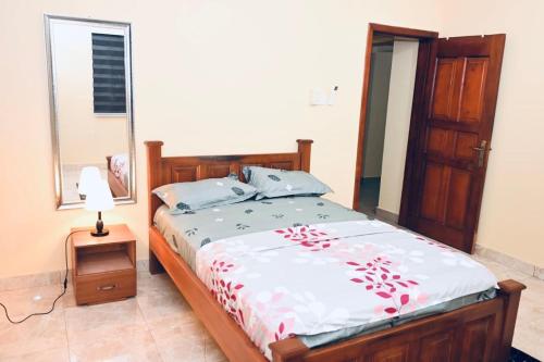 a bedroom with a bed and a mirror and a lamp at Huberta Haven in Accra