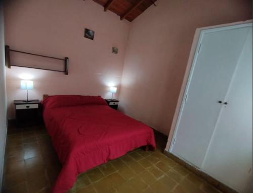 a bedroom with a red bed and two lamps on two tables at Deptos Pablos, Apto No 3 in Villa Gesell