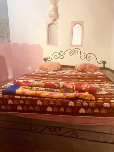 a bed with a quilt on it in a room at Auberge Culturelle Les Belles Etoiles in Abene
