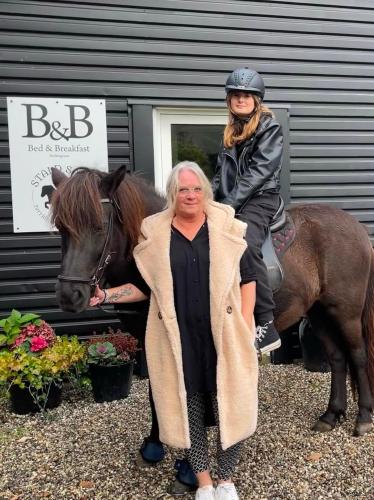 a woman sitting on a horse next to a man at B&B Saga in Herning