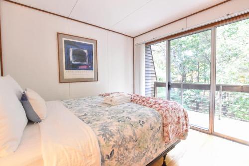 a bedroom with a bed and a large window at Architectural modern home 5 mins to beach in Truro