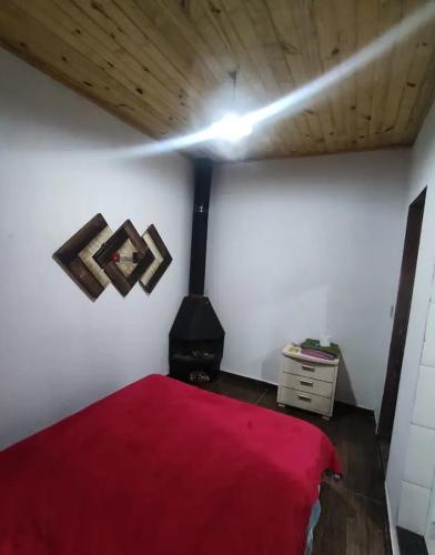 a bedroom with a red bed and a stove at Suíte da Vila in Visconde De Maua