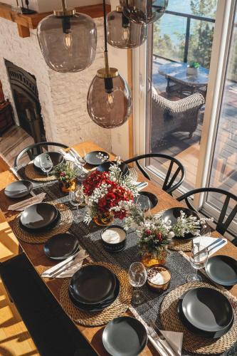 a wooden table with black plates and flowers on it at Villa Experience Nature Le Nid in Saint-Irénée