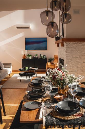 a dining room with a table with plates and wine glasses at Villa Experience Nature Le Nid in Saint-Irénée