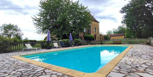 - une piscine dans une cour avec des chaises et des parasols dans l'établissement Domaine de Périer, à Cénac-et-Saint-Julien