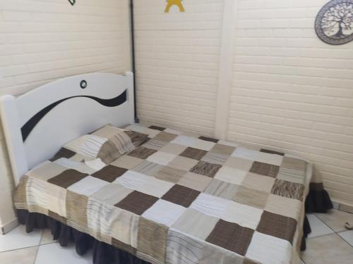 a bedroom with a bed with a checkered blanket at Pousada - Flat - Kitnet - Mobiliada, Confortável e Perto de Tudo in Atibaia