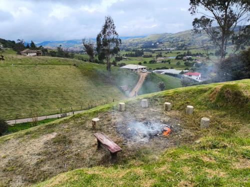 a fire in a field with a bench on a hill at Glamping con jacuzzi La Terraza del cielo in Chocontá