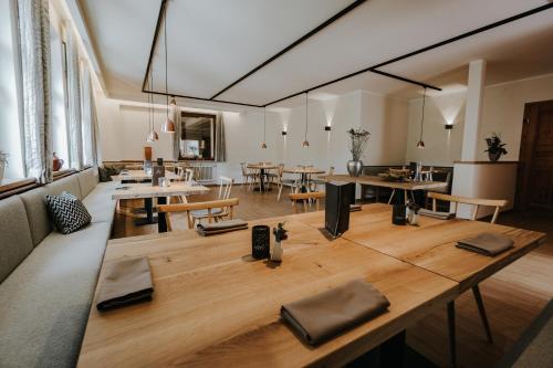 WeißenbrunnにあるGasthof Alexの木製のテーブルと椅子が備わる広い客室です。
