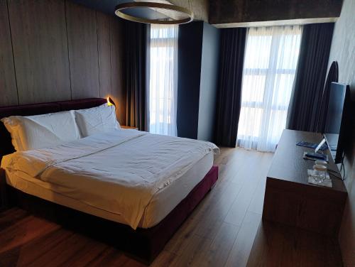 a bedroom with a large bed and a desk and windows at Toka Hotel Restaurant in Pogradec