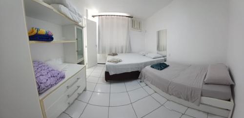 a white bedroom with two beds and a mirror at Gran Lencois Flat Residence in Barreirinhas