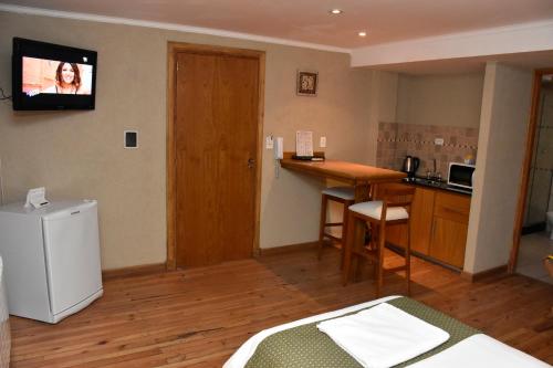um quarto com uma cozinha e uma televisão na parede em Bahia Belgrano Suites em Bahía Blanca