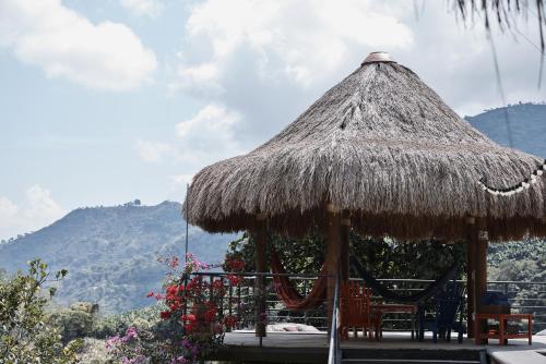 a straw hut with chairs and a hammock at Finca La Manchuria in Salgar