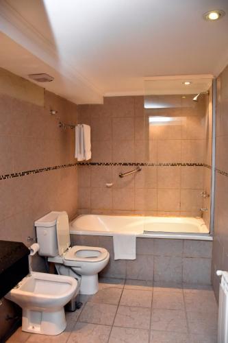 a bathroom with a toilet and a bath tub at Bahia Belgrano Suites in Bahía Blanca