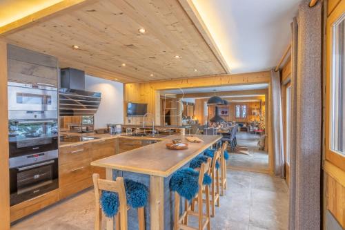 une cuisine avec une grande île dotée de chaises bleues dans l'établissement Chalet Le Hameau - Megève, à Demi-Quartier