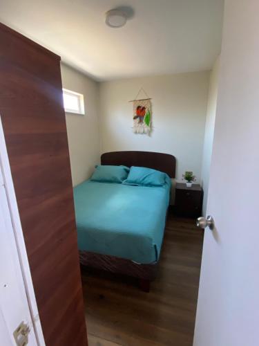 a bedroom with a bed with blue sheets at Mini casa aérea in Villarrica