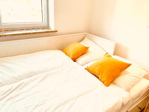 a white bed with two yellow pillows on it at Gemütliches Apartment mit Fernblick Kamin Balkon in Zwiesel