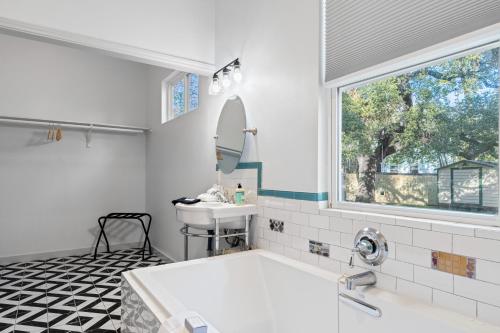 Un baño con bañera, lavabo y ventana. en 3 in 1 Villa Swing Set Game Room Dogs Ok, en Austin