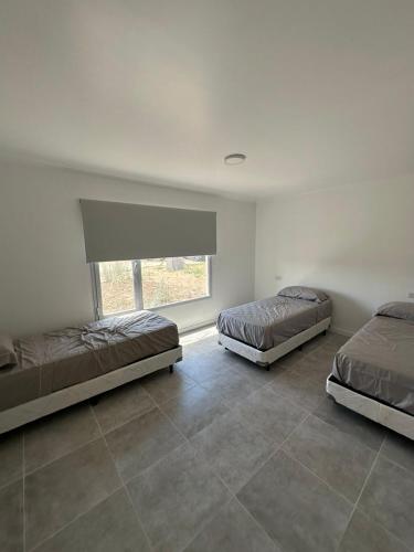 Dos camas en una habitación con ventana. en Casa barrio Las Lomas 2, en Monte Hermoso