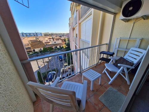 un balcon avec des chaises et une vue sur la ville dans l'établissement Évasion Marine - Plage du Grau-du-Roi, au Grau-du-Roi