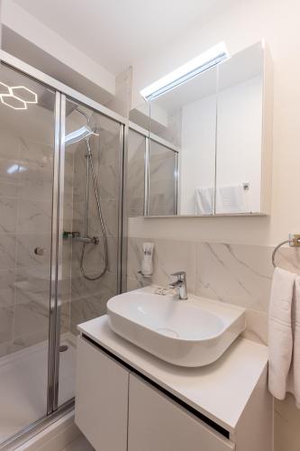 a white bathroom with a sink and a shower at Deluxe Appart & Hotel Zürich Kreis 4 in Zürich