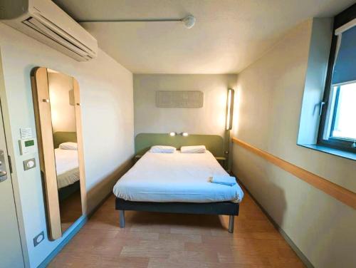 a small room with a bed and a mirror at Ibis Budget Clermont Ferrand - Le Brezet - Aeroport in Clermont-Ferrand