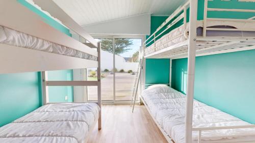 Dos literas en una habitación con paredes azules. en Les Flots des Demoiselles, en Plage-des-Demoiselles