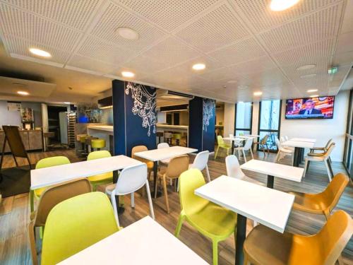 a restaurant with white tables and yellow chairs at Ibis Budget Clermont Ferrand - Le Brezet - Aeroport in Clermont-Ferrand