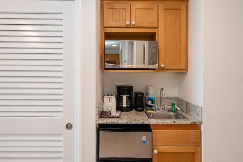 a small kitchen with a sink and a microwave at Wyndham Reef Resort, Grand Cayman in Sand Bluff