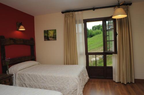 a bedroom with two beds and a large window at El Quesar de Gamoneo in Gamonedo de Cangas