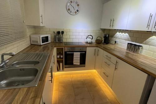 a kitchen with a sink and a clock on the wall at 3-Bed House Sleeps 5 w Garden Parking & Pets Ok in Norwich