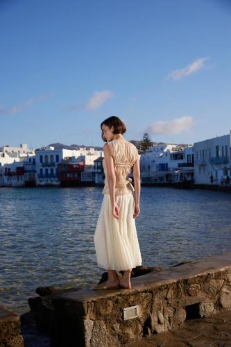 a woman in a white dress standing on a dock near the water at Mykonos Bay Resort & Villas in Mýkonos City