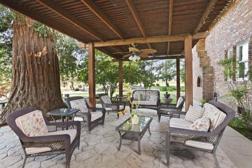 a patio with chairs and tables and a tree at Wine Country Oasis Private Pool & Spa in Acampo