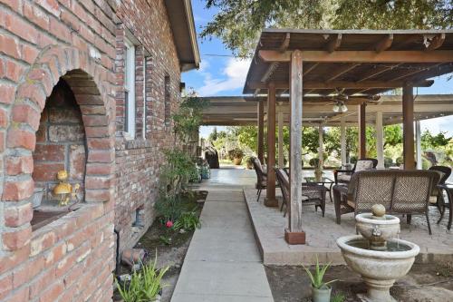 a brick building with an outdoor patio with a stone fireplace at Wine Country Oasis Private Pool & Spa in Acampo