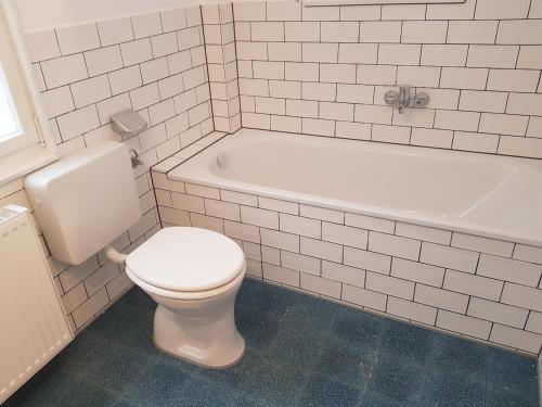 a white bathroom with a toilet and a bath tub at Wunderschönes Chalet mit Seeblick in Schluchsee