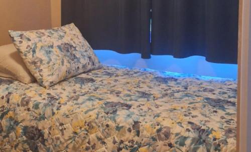 a bed with a flowered blanket with a pillow on it at Tiny Home Villa - T8 in San Diego