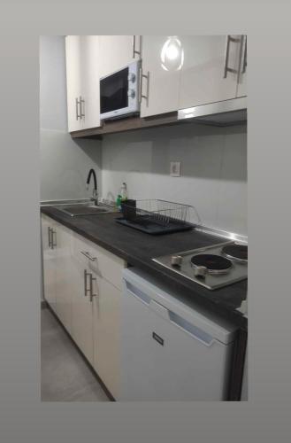 a kitchen with white cabinets and a sink and a microwave at BEST PARADISE IN NIKITI in Nikiti