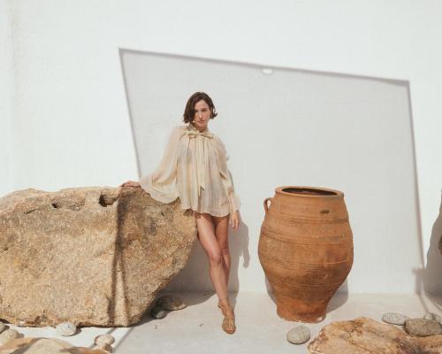 a woman in a dress sitting on a rock next to a vase at Mykonos Bay Resort & Villas in Mýkonos City
