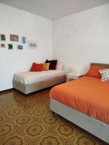 a bedroom with two beds with orange and yellow pillows at Casa Anteresa in Vietri sul Mare