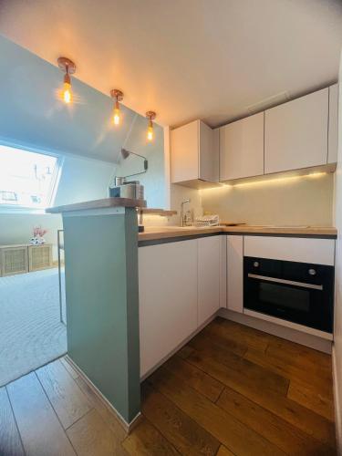 une cuisine avec des armoires blanches et un appareil noir dans l'établissement Cozy flat, à Paris