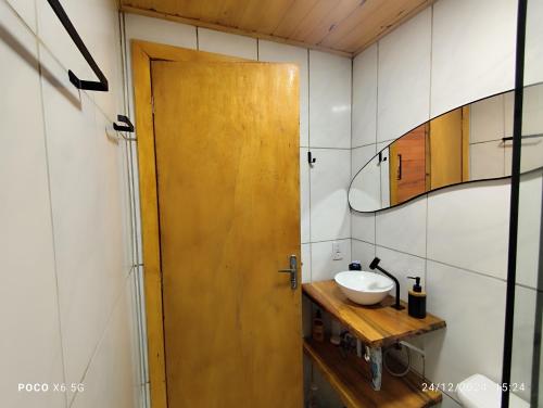 a bathroom with a wooden door and a sink at Janela do céu chalés in Maquiné
