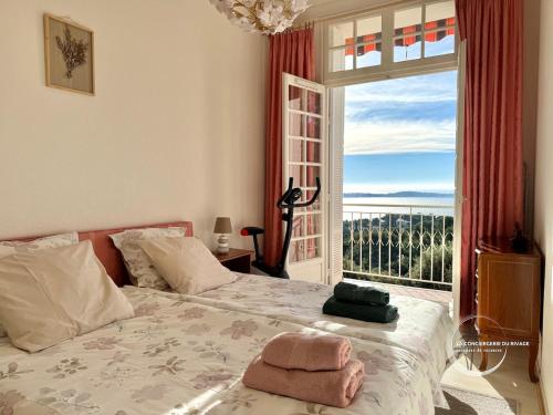 une chambre avec un lit et une grande fenêtre dans l'établissement Le Mont des Oiseaux - Piscine - Vue panoramique, à Hyères