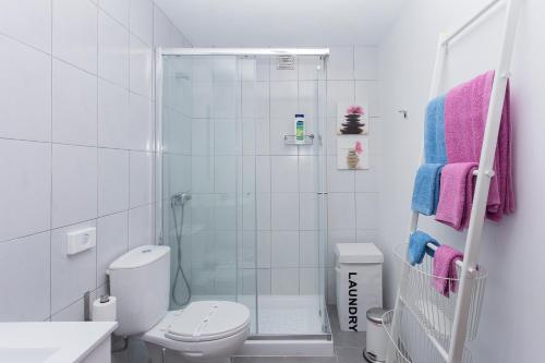 a white bathroom with a shower and a toilet at Garden Apartment, great for couple - Ponta Delgada in Ponta Delgada