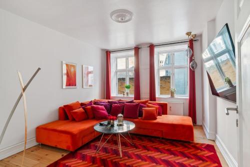 a living room with a red couch and a table at Best Location - 5 Min To Tivoli And Main Station in Copenhagen