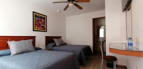 a bedroom with two beds and a ceiling fan at Hotel Camba in Oaxaca City