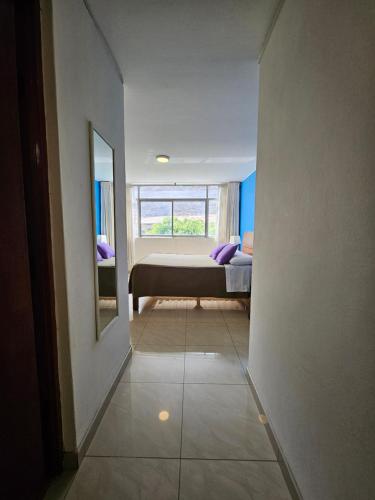 a hallway to a bedroom with a bed and a mirror at Hotel Acuario in Churín