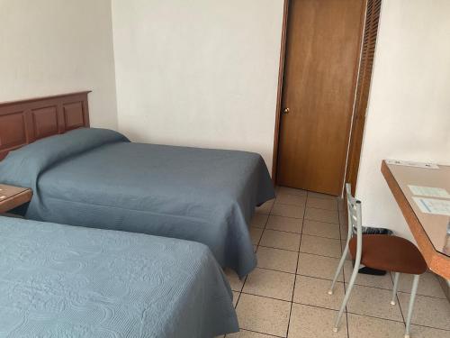 a room with two beds and a table and a desk at Hotel Camba in Oaxaca City